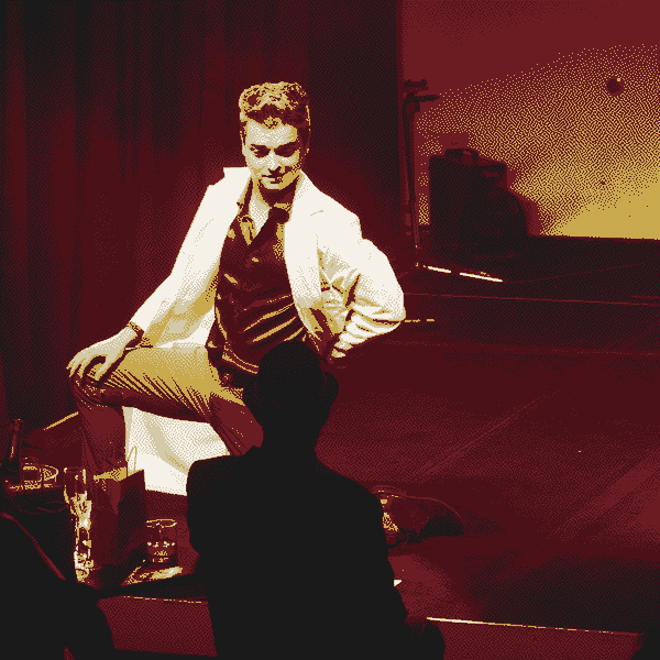 Luci, performing as Professor Oak kneels on the edge of the stage and seductively stares down a man in a hat.